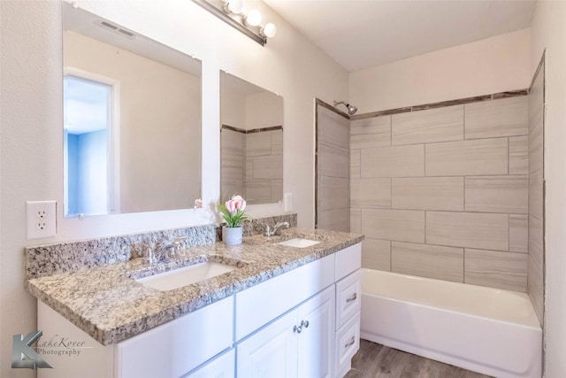 full bath with visible vents, a sink, shower / bathing tub combination, and wood finished floors