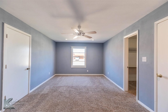 unfurnished bedroom featuring ceiling fan, carpet flooring, a walk in closet, and baseboards