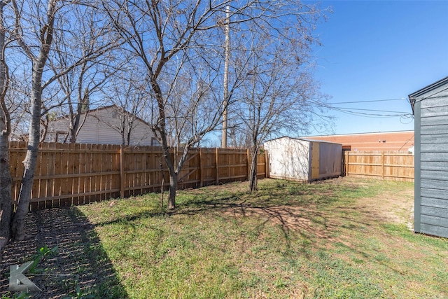 view of yard with a fenced backyard, a storage unit, and an outdoor structure