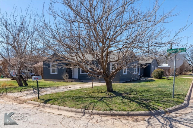 obstructed view of property with concrete driveway and a front lawn