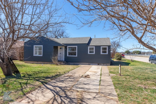 view of front of house featuring driveway, a shingled roof, and a front yard