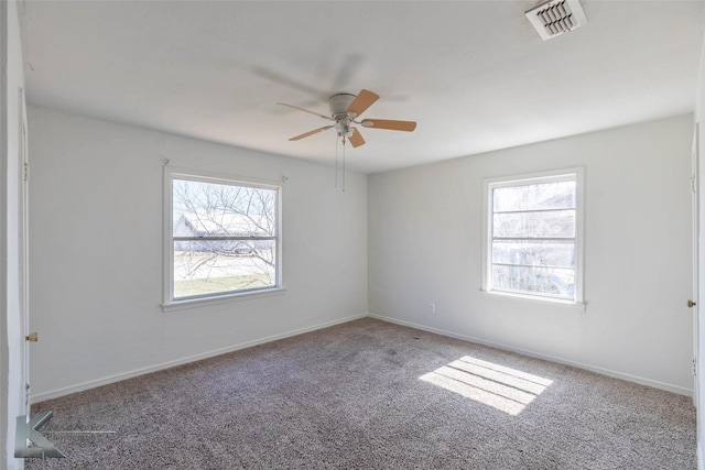 carpeted spare room with baseboards, visible vents, and a wealth of natural light