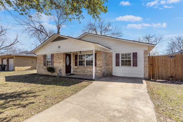 view of front of house featuring covered porch, brick siding, a front lawn, and fence