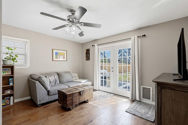 living room with light wood-type flooring, baseboards, a ceiling fan, and french doors