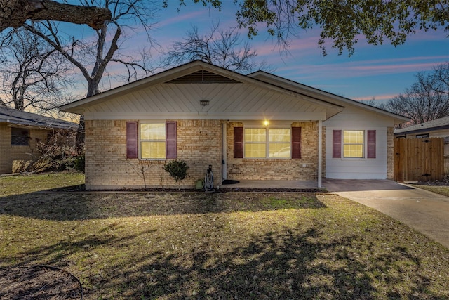 ranch-style home with a front yard, brick siding, and fence