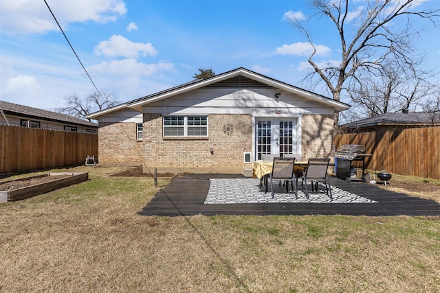 back of house with brick siding, fence, a garden, a yard, and french doors