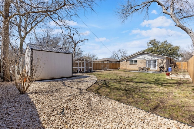 view of yard featuring french doors, a patio area, a shed, a fenced backyard, and an outdoor structure