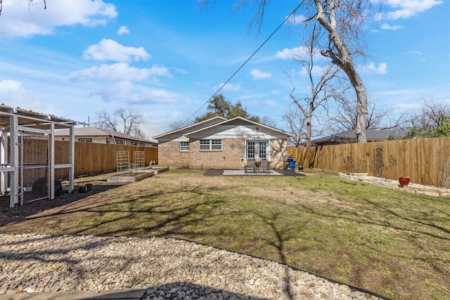 back of property featuring a lawn, a patio area, a fenced backyard, and a garden