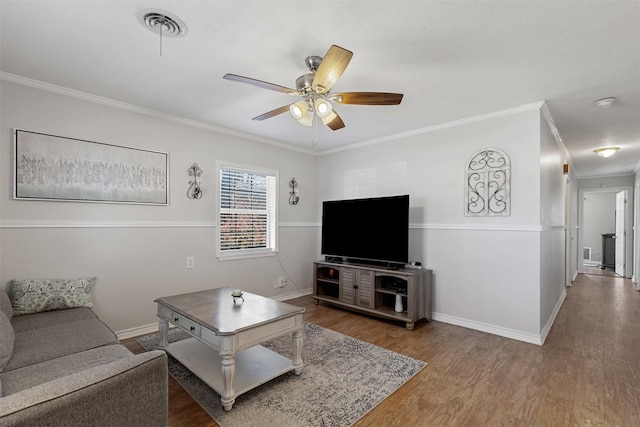 living room with baseboards, wood finished floors, visible vents, and crown molding