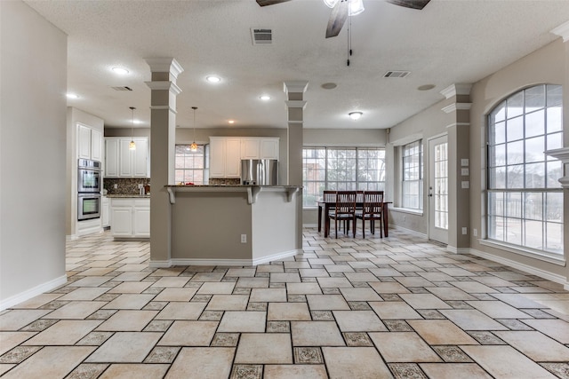 kitchen with a breakfast bar area, visible vents, stainless steel appliances, and backsplash