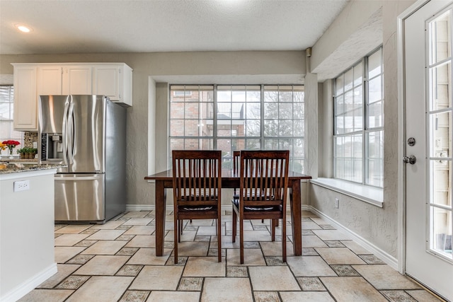 dining room with recessed lighting, stone tile floors, and baseboards