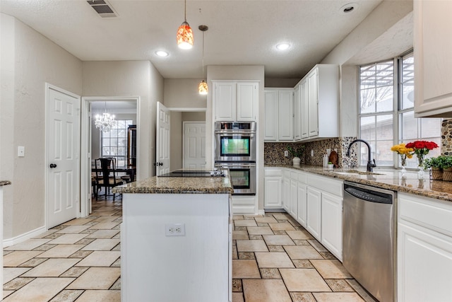 kitchen with stainless steel appliances, white cabinetry, visible vents, a center island, and tasteful backsplash