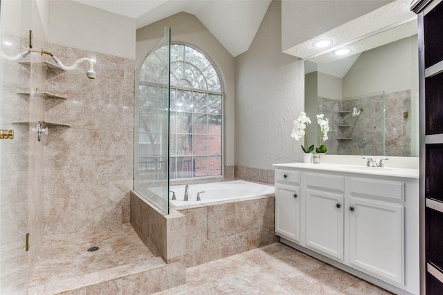 bathroom featuring lofted ceiling, a textured wall, vanity, a tile shower, and a bath