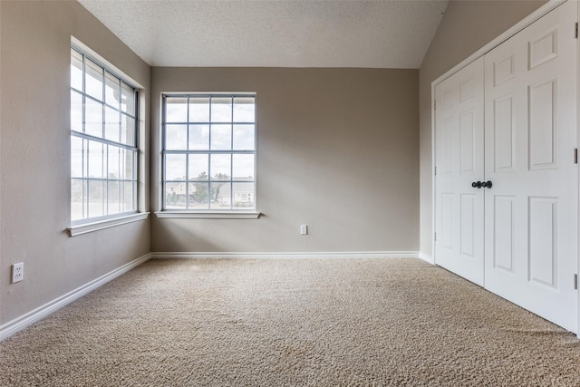 unfurnished bedroom with carpet floors, multiple windows, and a textured ceiling