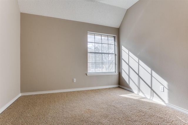 spare room featuring a textured ceiling, carpet, lofted ceiling, and baseboards