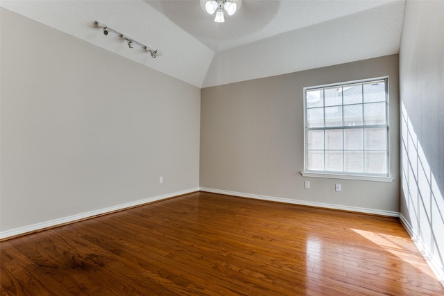 unfurnished room with a ceiling fan, wood-type flooring, vaulted ceiling, and baseboards