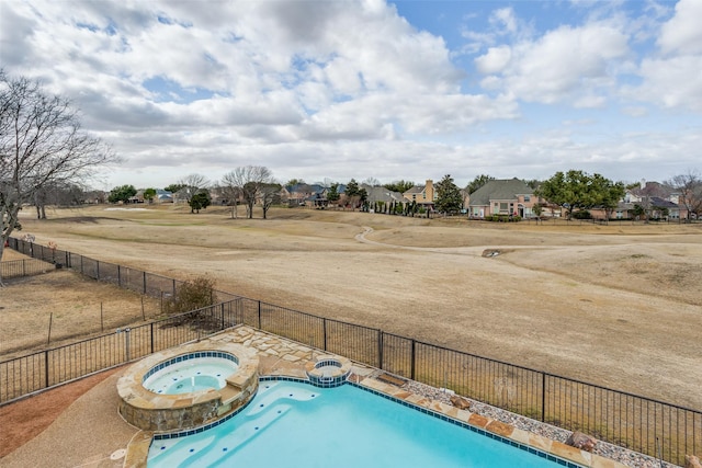 view of swimming pool featuring a residential view, a pool with connected hot tub, and fence