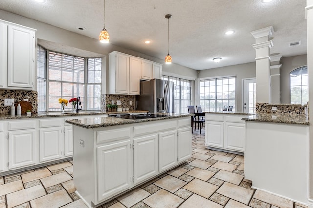 kitchen with stainless steel fridge, decorative backsplash, a kitchen island, black electric stovetop, and a sink