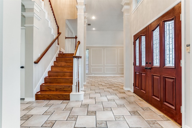 entryway with a decorative wall, a towering ceiling, baseboards, visible vents, and stairway