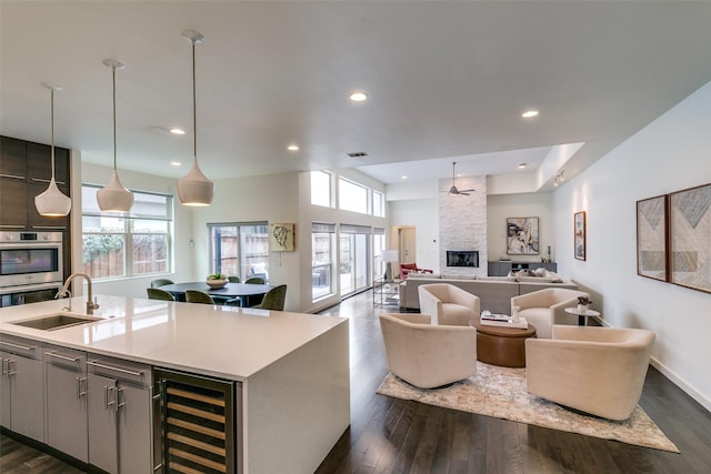 kitchen with dark wood-type flooring, open floor plan, a sink, beverage cooler, and plenty of natural light