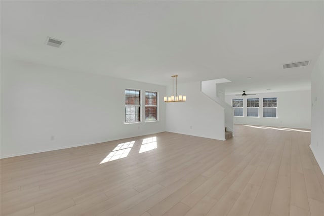 interior space with ceiling fan with notable chandelier, baseboards, visible vents, and light wood-style floors