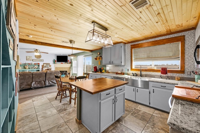 kitchen with a tile fireplace, wood ceiling, butcher block countertops, open floor plan, and gray cabinets