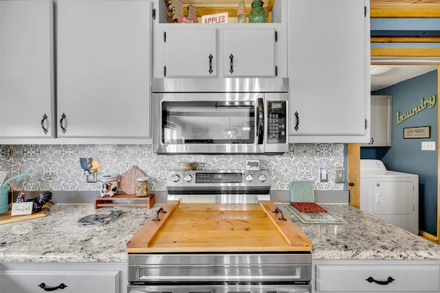 kitchen with washer / dryer, white cabinetry, stainless steel appliances, and decorative backsplash