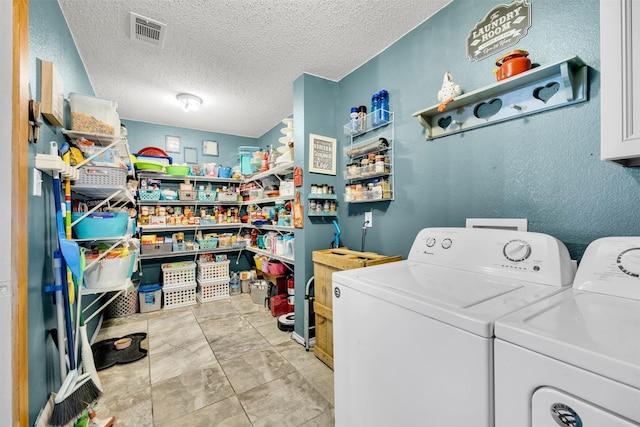 washroom featuring a textured ceiling, laundry area, washer and clothes dryer, and visible vents