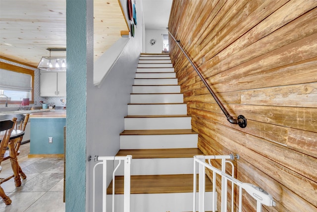 stairs featuring wood walls and tile patterned floors