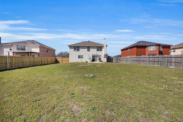 rear view of house featuring a fenced backyard and a lawn