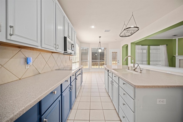 kitchen featuring light tile patterned floors, blue cabinets, a sink, visible vents, and appliances with stainless steel finishes