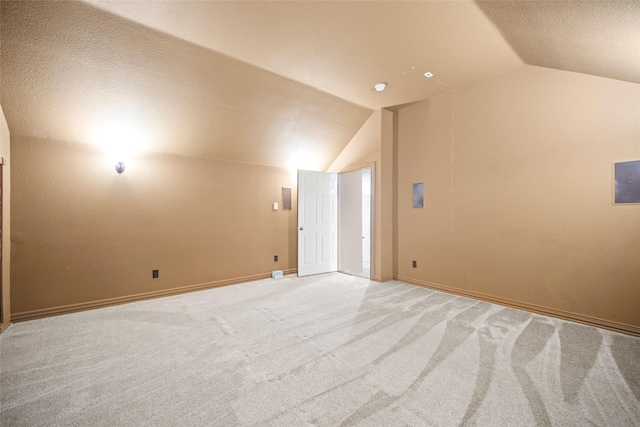 spare room featuring lofted ceiling, a textured ceiling, baseboards, and light colored carpet