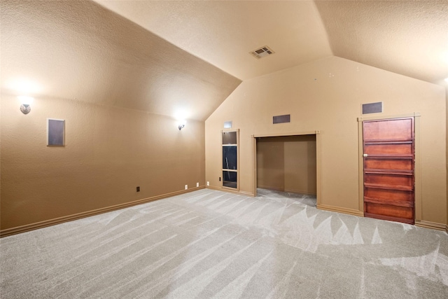 bonus room featuring lofted ceiling, visible vents, light carpet, a textured ceiling, and baseboards