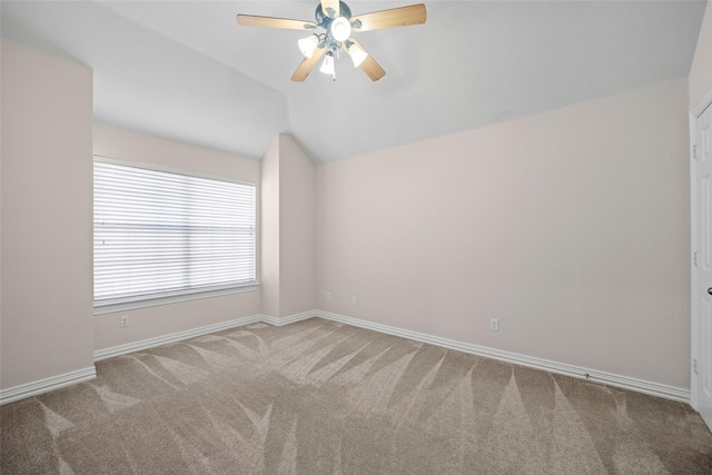 carpeted spare room featuring a ceiling fan, lofted ceiling, and baseboards