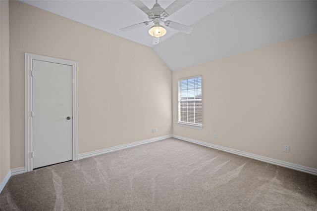 empty room with a ceiling fan, lofted ceiling, carpet flooring, and baseboards