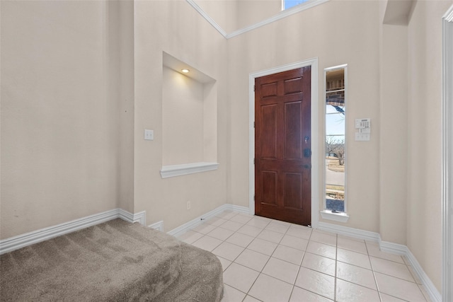 entryway with light tile patterned floors, a high ceiling, and baseboards