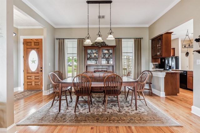 dining area with light wood-style floors, visible vents, and crown molding