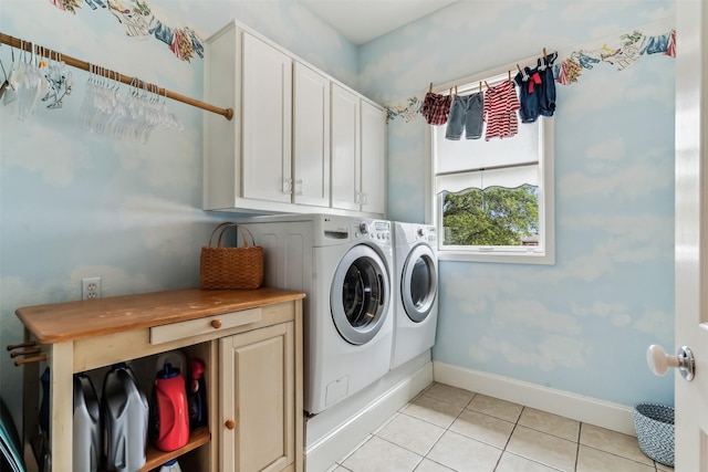 washroom featuring separate washer and dryer, light tile patterned flooring, cabinet space, and baseboards