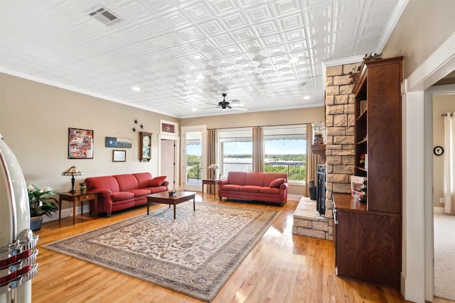 living area featuring an ornate ceiling, crown molding, visible vents, and wood finished floors