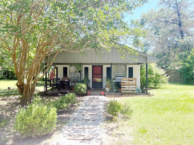 view of front facade featuring a porch, a front lawn, and fence