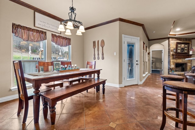 dining room with baseboards, tile patterned floors, crown molding, a fireplace, and a chandelier