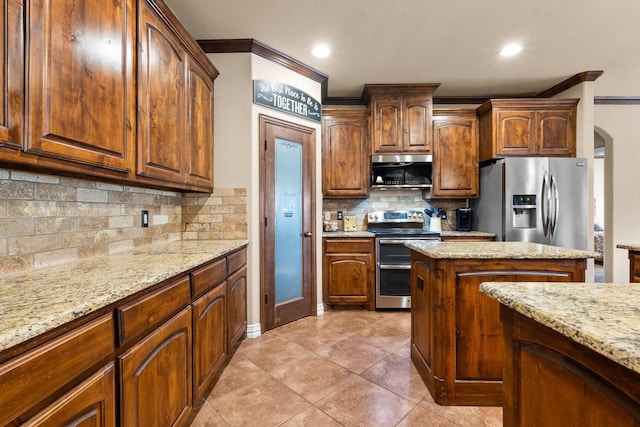 kitchen with light stone counters, arched walkways, crown molding, stainless steel appliances, and backsplash