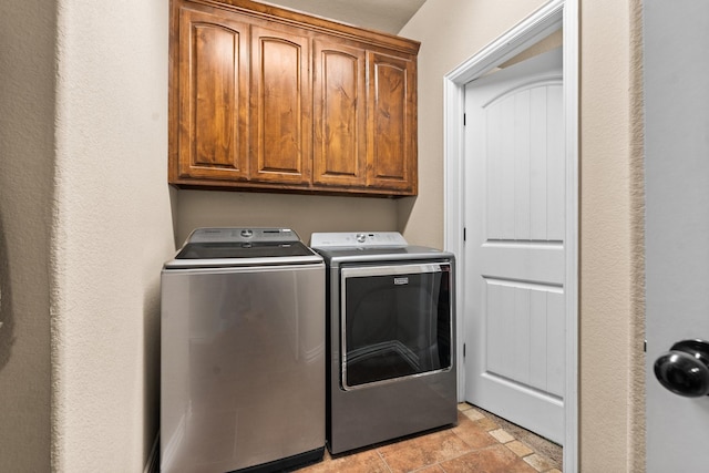 laundry room with stone finish floor, washing machine and clothes dryer, and cabinet space