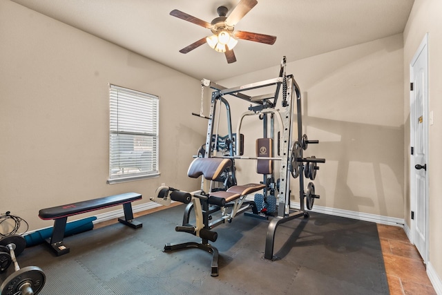 exercise room with ceiling fan and baseboards