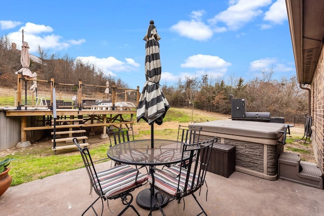 view of patio / terrace with a hot tub, fence, and outdoor dining space