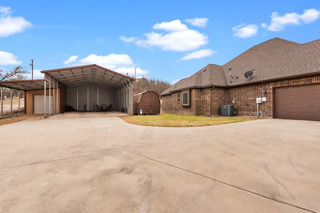 view of property exterior featuring concrete driveway, an outbuilding, a shed, central AC, and brick siding