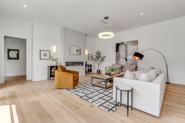 living room with light wood-type flooring, recessed lighting, a fireplace, and baseboards