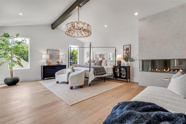 bedroom with beamed ceiling, a glass covered fireplace, multiple windows, and wood finished floors