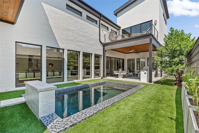 rear view of house with a patio, a balcony, fence, a ceiling fan, and a yard