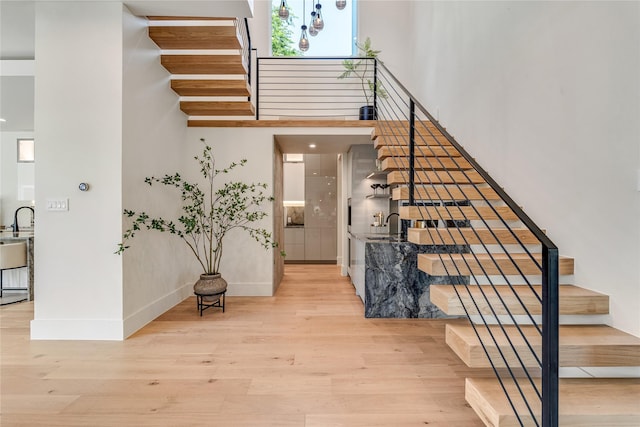 staircase with a towering ceiling, baseboards, and wood finished floors